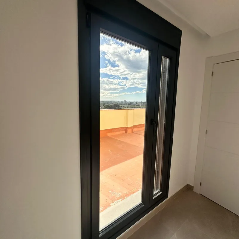 Puerta balconera de aluminio antracita con fijo lateral y salida a una terraza