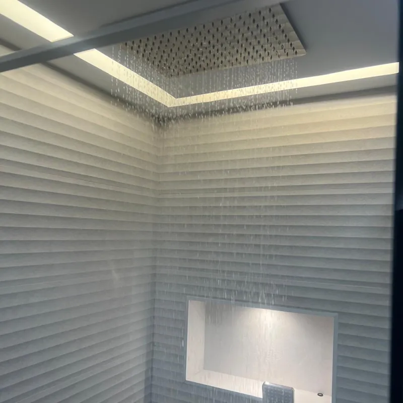 Ducha efecto lluvia empotrada en el techo, en funcionamiento, con hornacina iluminada y azulejo con relieve