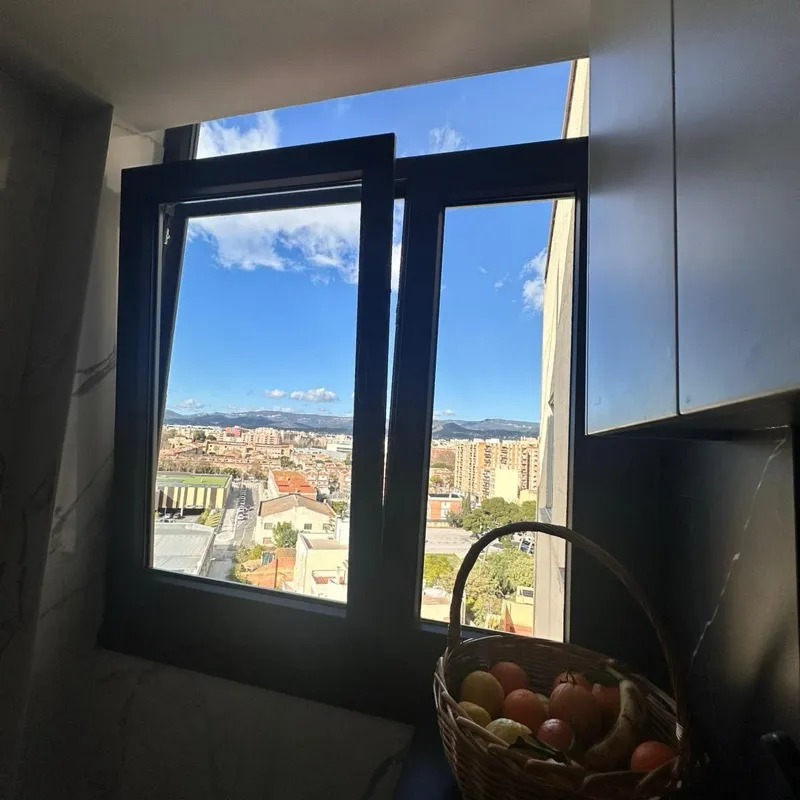 Ventana practicable de aluminio de dos hojas en una cocina, con vistas a la ciudad